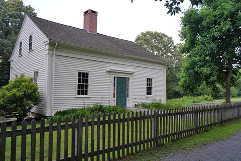 White, two-story house with brick center chimney and green door