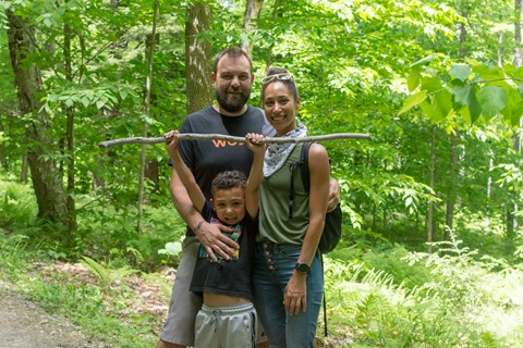 Two adults and one child on a trail pose for photo