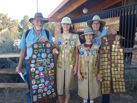 Four visitors with long vests full of golden badges.