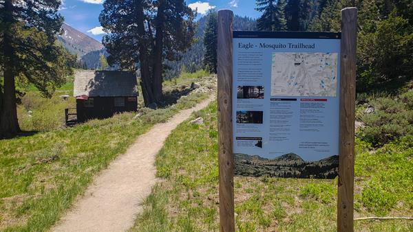 Eagle-Mosquito Trailhead sign with cabin in background.