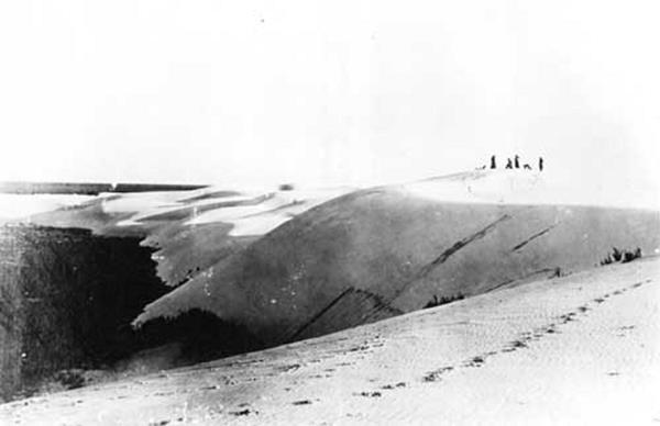 A grainy, black and white photo of visitors on the dunes at White Sands.