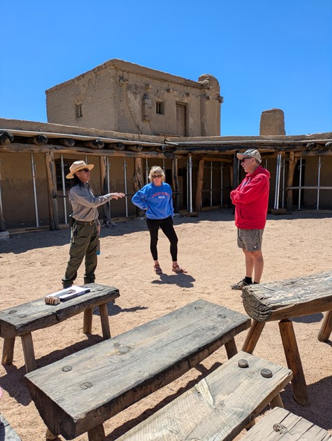 A park ranger talks to two visitors inside a plaza of the reconstructed fort.