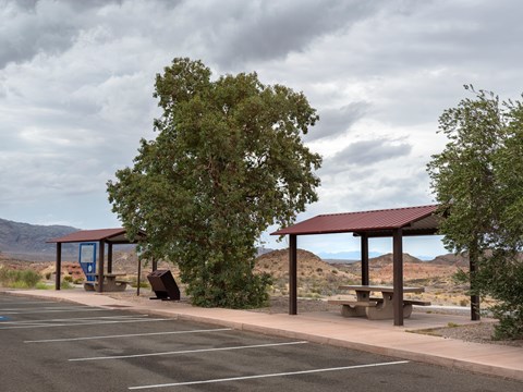 Two picnic shelters next to a parking lot