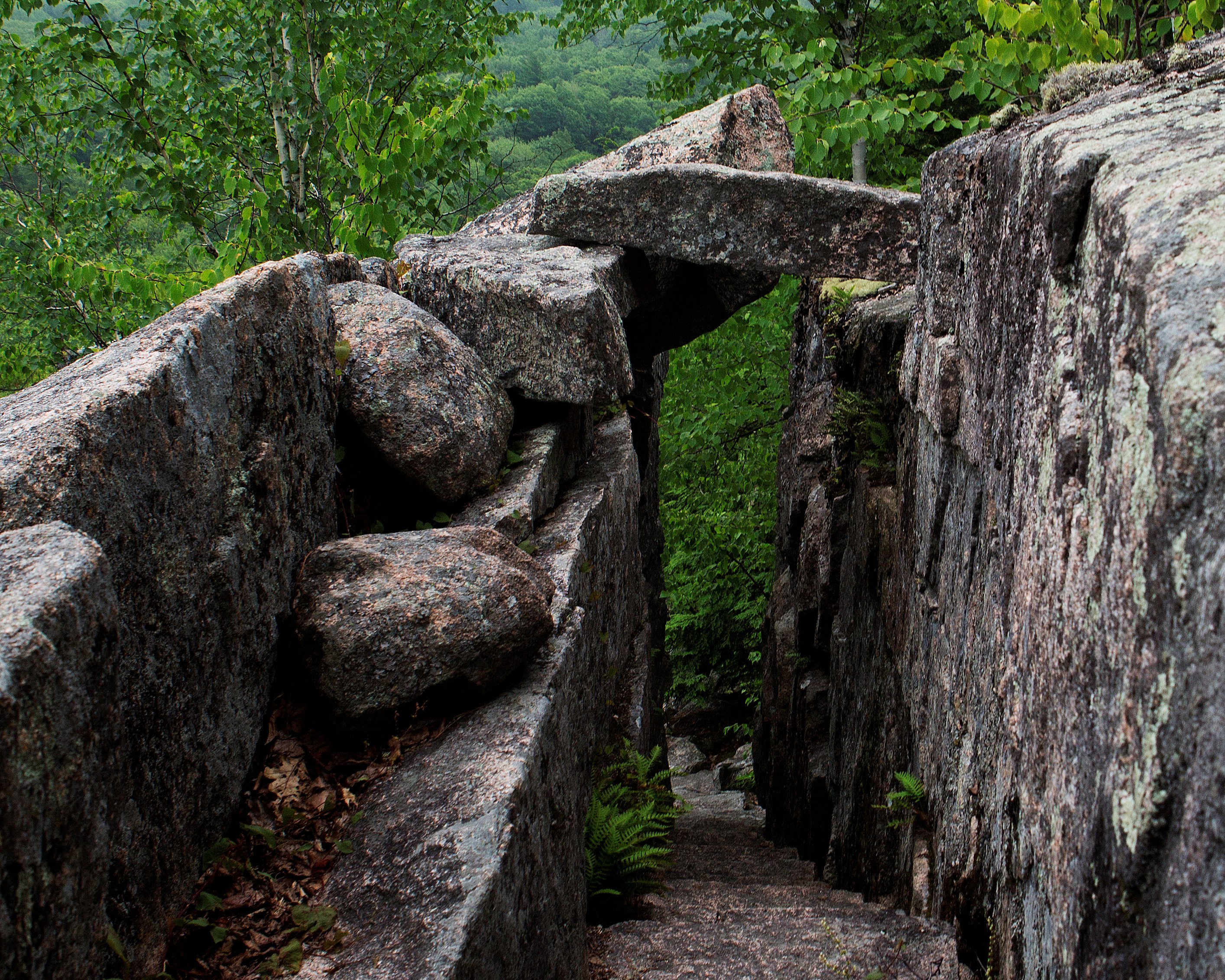 Rock bridge over a trail cut into granite