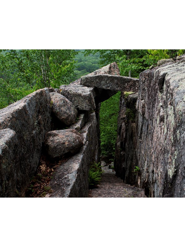 Rock bridge over a trail cut into granite