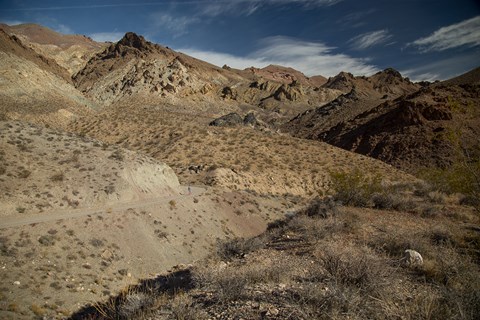 A woman running along a dirt road in a diverse desert setting.