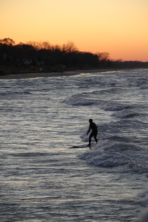 Surfer rides the waves at Portage Lakefront and Riverwalk at the Indiana Dunes National Park.