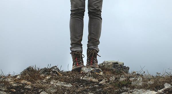 A close up of a hiker's boots standing on a rock cliff.
