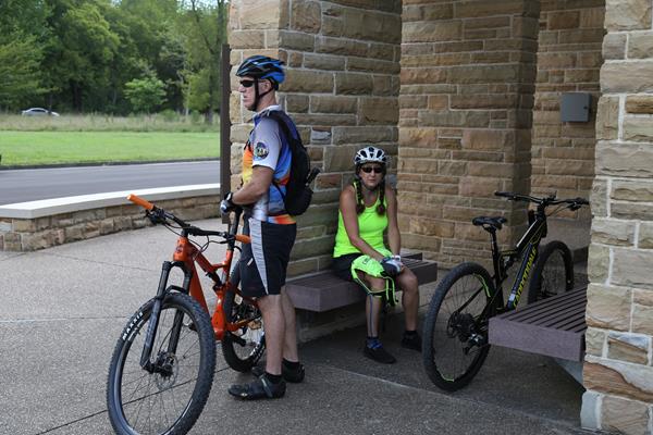 Two people with bikes resting on a bench.