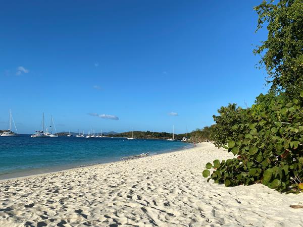 A wide, white sand beach slopes gently down to turquoise water.