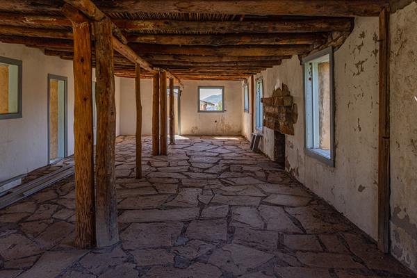 Interior of line camp with flagstone floor, reed ceiling, and white-washed stucco walls.