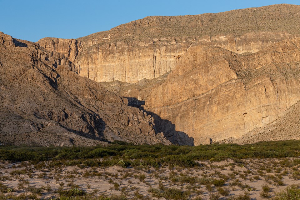 The Rio Grande flows through a large canyon that cuts the tall limestone cliffs.