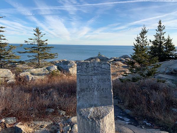 a wooden sign with in front of ocean view and trees