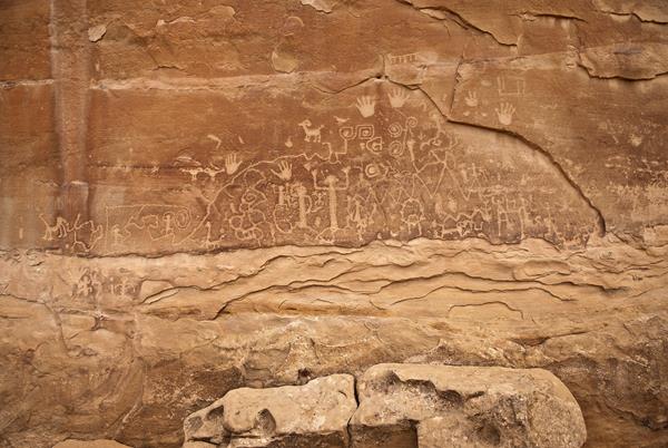 Red-colored sandstone with pecked geographic, animal, and human figures.