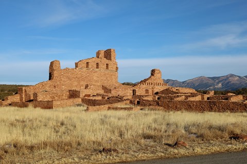 Red sandstone church ruins with mountains in the background