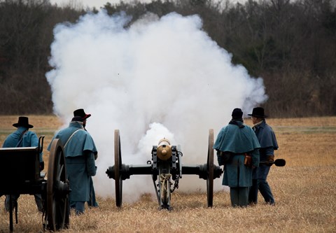 Men in blue wool uniforms fire a bronze cannon.