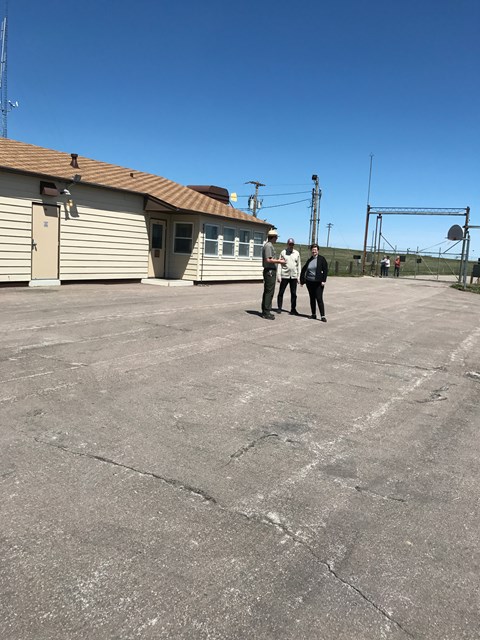 A park ranger with visitors inside a fenced compound