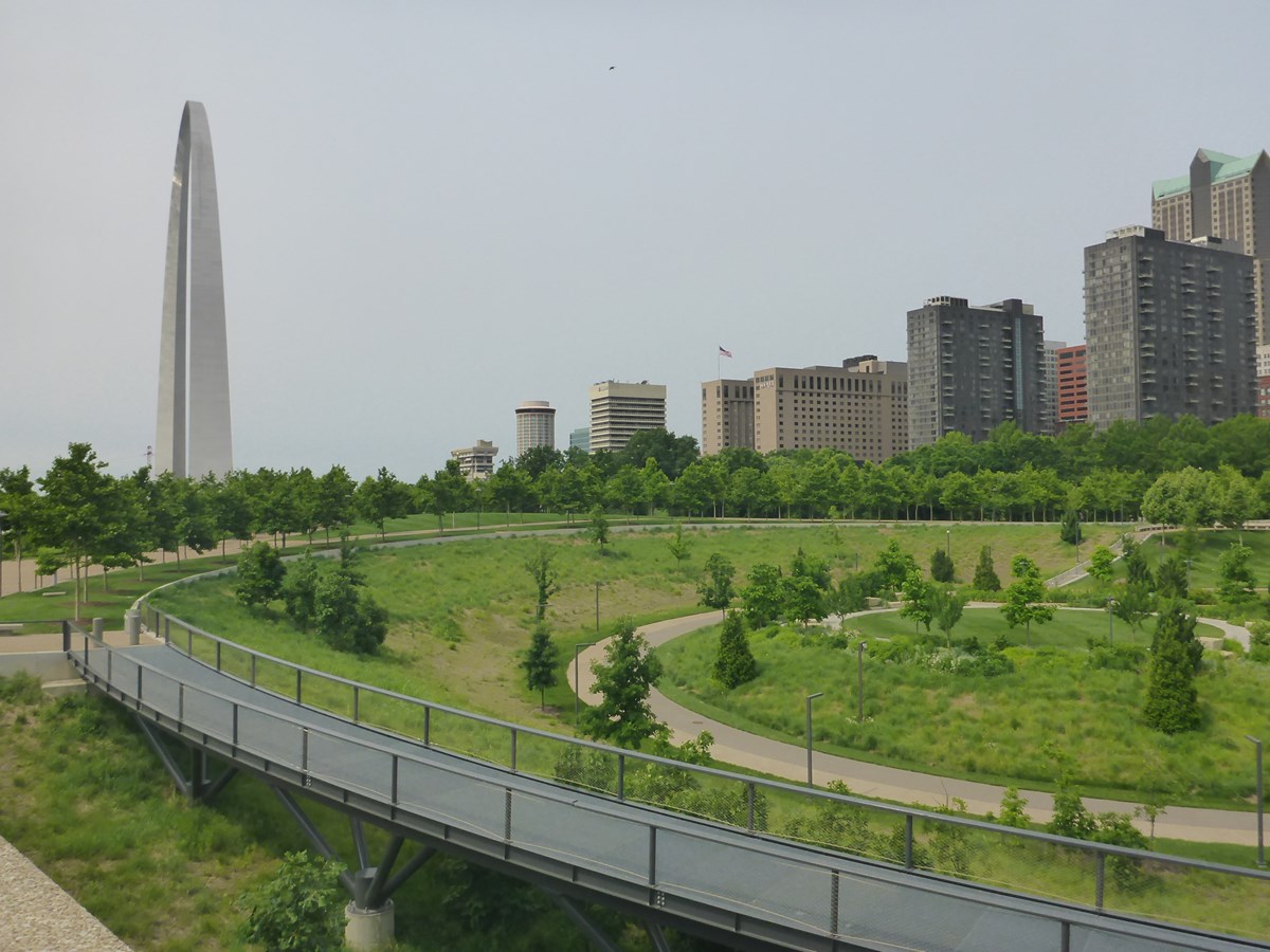 A green space with the city and gateway arch in the background