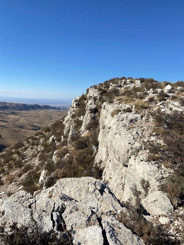 A desert mountain ends abruptly with a grey cliff
