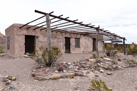 2-room adobe structure with a metal ramada over the front doors