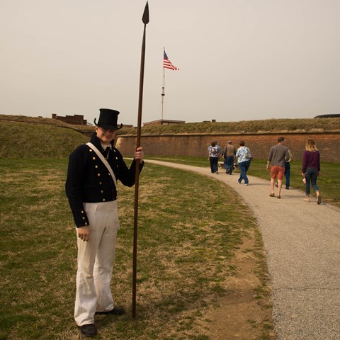 A living historian greets visitors at the entrance of the historic zone.