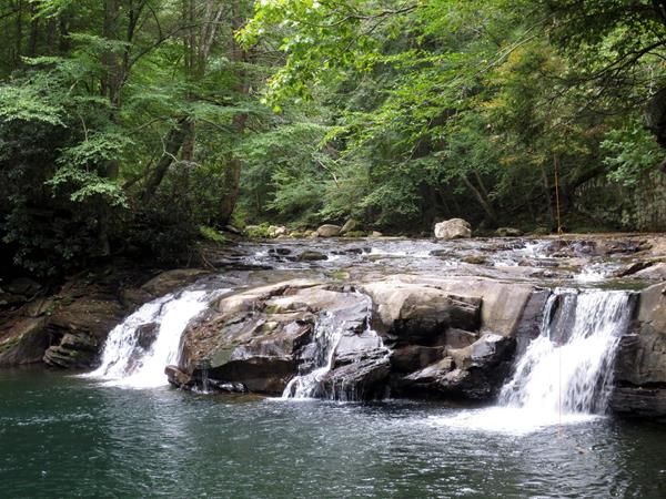 A view of a waterfall into a deep pool along the trail.