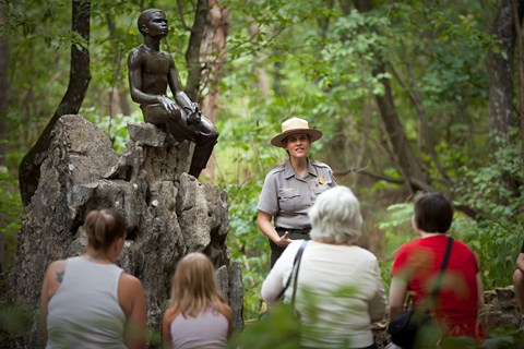 A park ranger conducting a guided tour to three adults and one child.