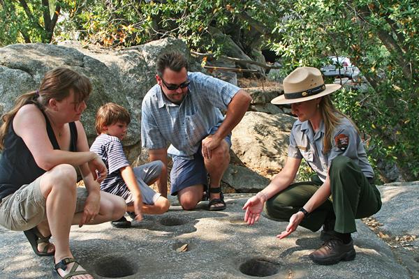 a ranger and a family examine mortar holes