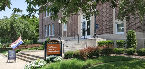 Signs in front of a brick Beaux-Arts style building state that the visitor center is open.