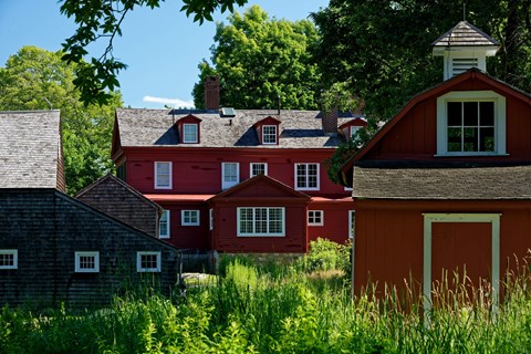 A back of a red house with two other buildings in front of it.