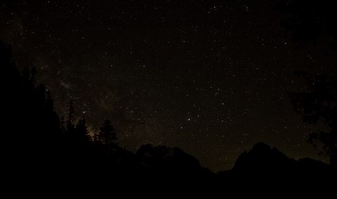 A starry night sky above a ridge of rocky mountain peaks.