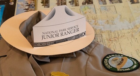 A shirt with a junior ranger badge, patch and hat on it.