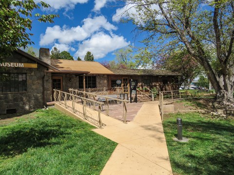 A small log and stone building sits set back from the sidewalk.