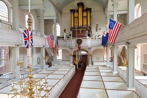Interior of Old North Church with box pews and flags hanging from the gallery.