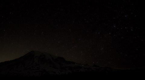 A starry sky stretches above a large volcanic peak.