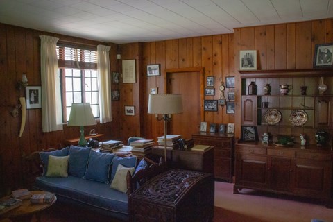 A living room with large desk near a fireplace.