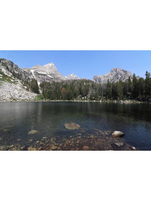 An alpine lake sits beneath rocky mountain peaks.