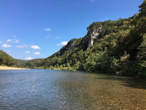 The river flanked by a bluff on the right side and a gravel bar on the left side.