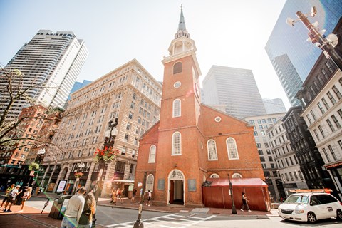 A brick two-story meeting house with a tall white steeple