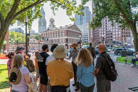 Ranger talking to a group of people. Faneuil Hall stands in the background.