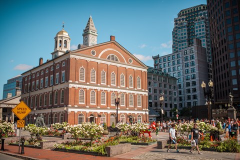 Three story brick building with white furnishes and a white and gilded cupola atop.