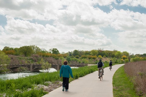 Two hikers and one bicyclist recreate on the Hike and Bike Trail next to the San Antonio River.