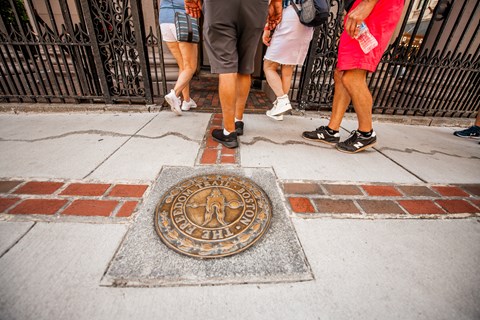 Circular metal medallion surrounded by brick that says "The Freedom Trail Boston"