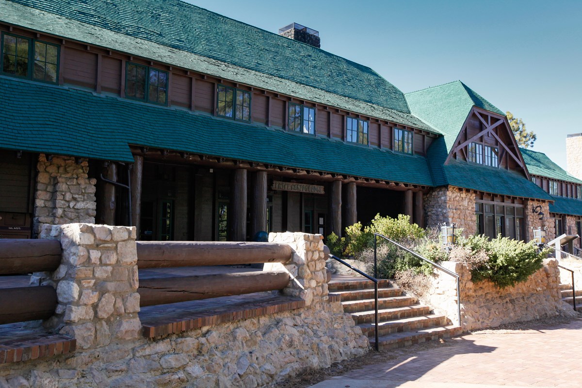 A large historic building with stone base, brown wood, and a green roof