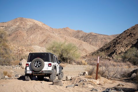 A Jeep turns from one dirt road to another next to a boundary marker.