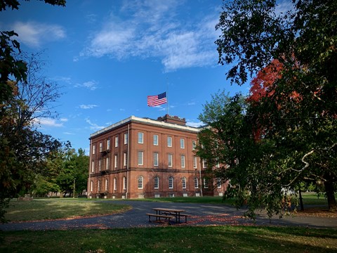 Springfield Armory, with the flag at half staff, with a path and a picnic table visible.