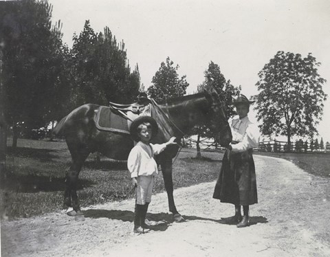 A young Ted Jr stands next to a horse led by his older sister Alice on the grounds of Sagamore Hill.