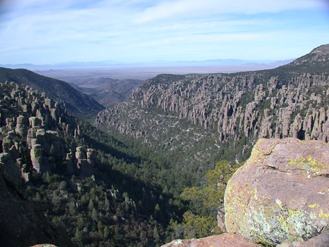 Green valley in distance lined with rock pinnacles