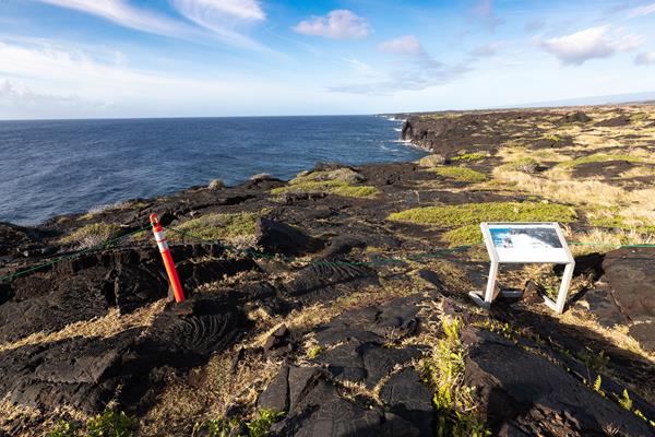A viewpoint of dramatic sea cliffs with a wayside exhibit in the foreground