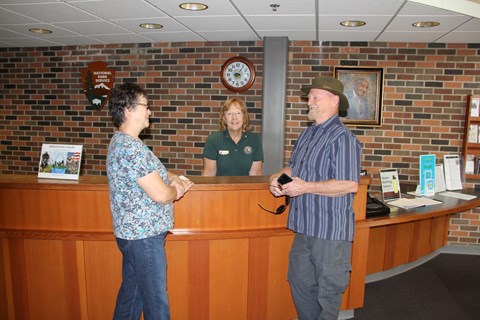 Two visitors talking to a park volunteer at the information front desk.